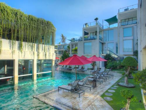 勒吉安巴厘岛水明漾富丽华海滩酒店的大楼前的带椅子和遮阳伞的游泳池