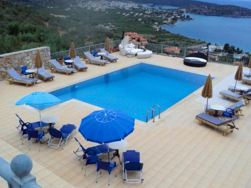 古厄庇道鲁斯Epidavros Seascape的一个带蓝色椅子和遮阳伞的游泳池