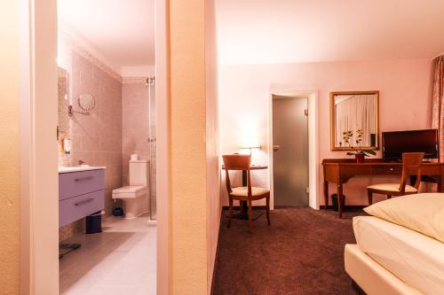 巴登-巴登施沃尔泽瓦尔索纳旅馆的一间卧室配有一张床,浴室设有书桌