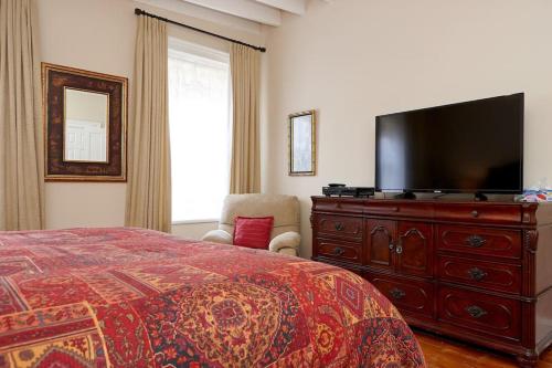卡利登切尔滕纳姆套房酒店的一间卧室配有一张床和一个带平面电视的梳妆台。