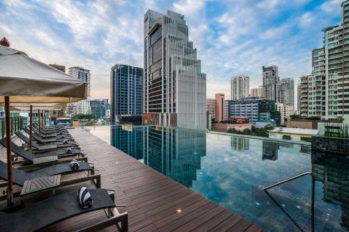 曼谷SKYVIEW Hotel Bangkok - Sukhumvit的一个带躺椅的屋顶游泳池和城市天际线