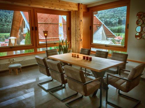 玛豪森伊泰尔Akzent Hotel Höhenblick的一间带木桌和椅子的用餐室
