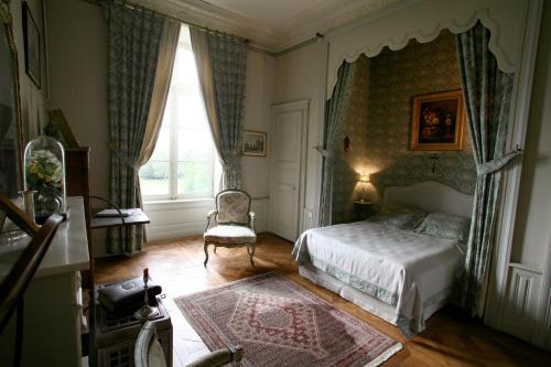 Sens-Beaujeu泊欲堡酒店的卧室配有床、椅子和窗户。