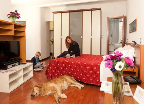 热那亚海尔薇堤亚酒店的坐在床上的女人,狗躺在地板上
