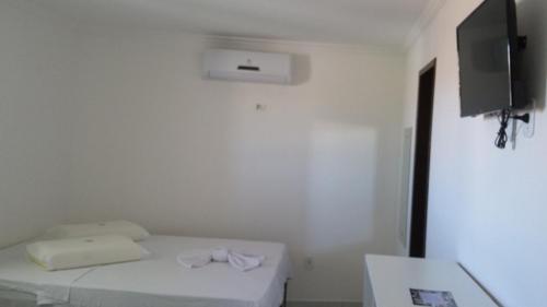 Currais Novos鲍萨达曼克斯酒店的一间白色的小房间,配有床和电视