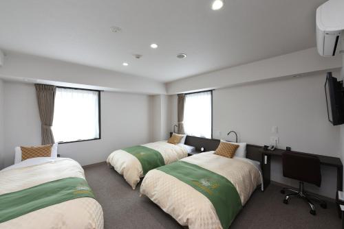 三岛市休美坎酒店的客房设有三张床、一张书桌和窗户。