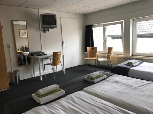 奥尔登扎尔Stadshotel Ter Stege的酒店客房带两张床和一张桌子以及椅子。
