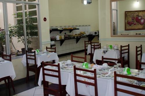 里约布兰科Hotel Majú的一间设有白色桌椅的用餐室