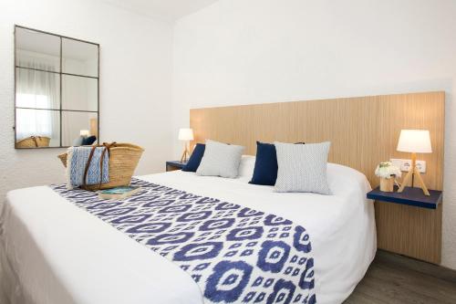 布拉内斯布拉内斯海滩皮埃尔假日公寓的卧室配有带蓝色枕头的大型白色床