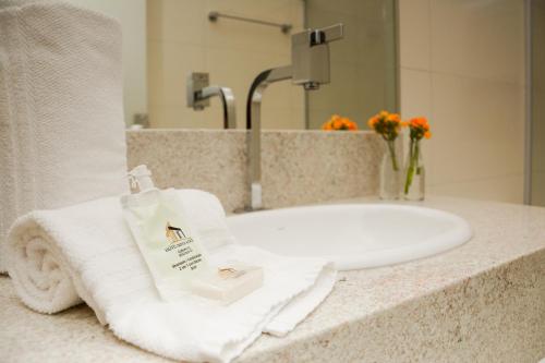 古鲁皮Hotel Imperador的浴室水槽和柜台上的白色毛巾