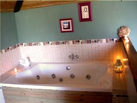 Reinosilla莫利诺德拉维加旅馆的浴室设有浴缸,墙上有两张照片