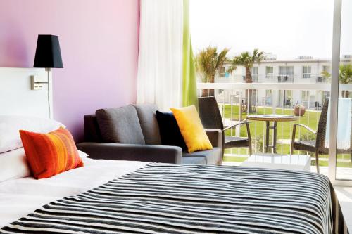 阿依纳帕Sunprime Ayia Napa Suites - Adults Only的酒店客房带一张床、椅子和一个阳台