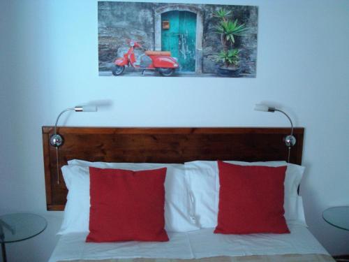 CaltignagaResidenza Le Palme的一张带两个红色枕头的床和一张摩托车照片