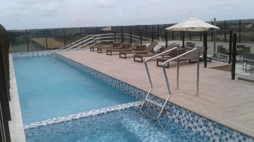 卡博迪圣阿戈斯蒂尼奥Intercity Suape Costa Dourada的大楼内一个带长椅和遮阳伞的游泳池