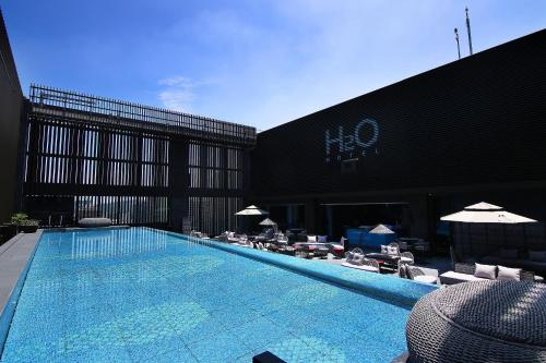 高雄水京栈国际酒店 的一座带椅子和遮阳伞的游泳池位于一座建筑旁边