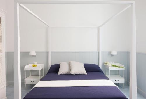 法维尼亚纳美丽度假酒店的白色和蓝色的卧室,配有床和两张桌子