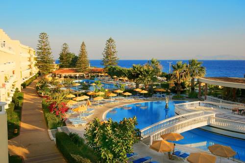 伊利索斯阳光罗德岛酒店的一个带遮阳伞和海洋的游泳池的度假酒店