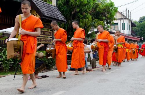 琅勃拉邦切特达拉别墅酒店的一群身着橙色长袍的僧侣沿着街道走去